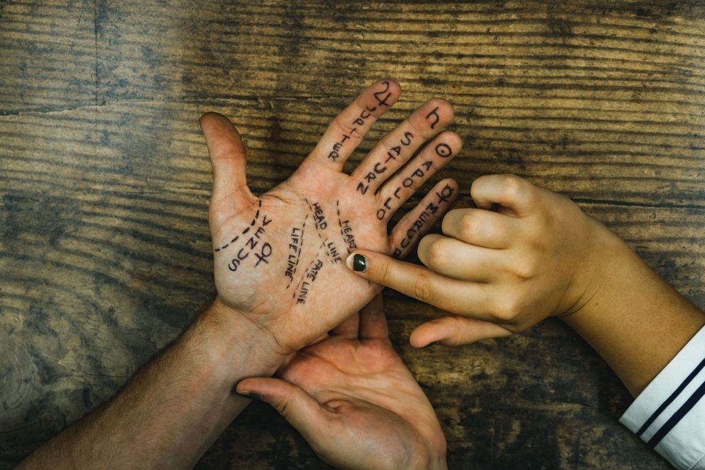 A fortune-teller conducting a palm reading, with lines and mounts marked out on the person's left palm